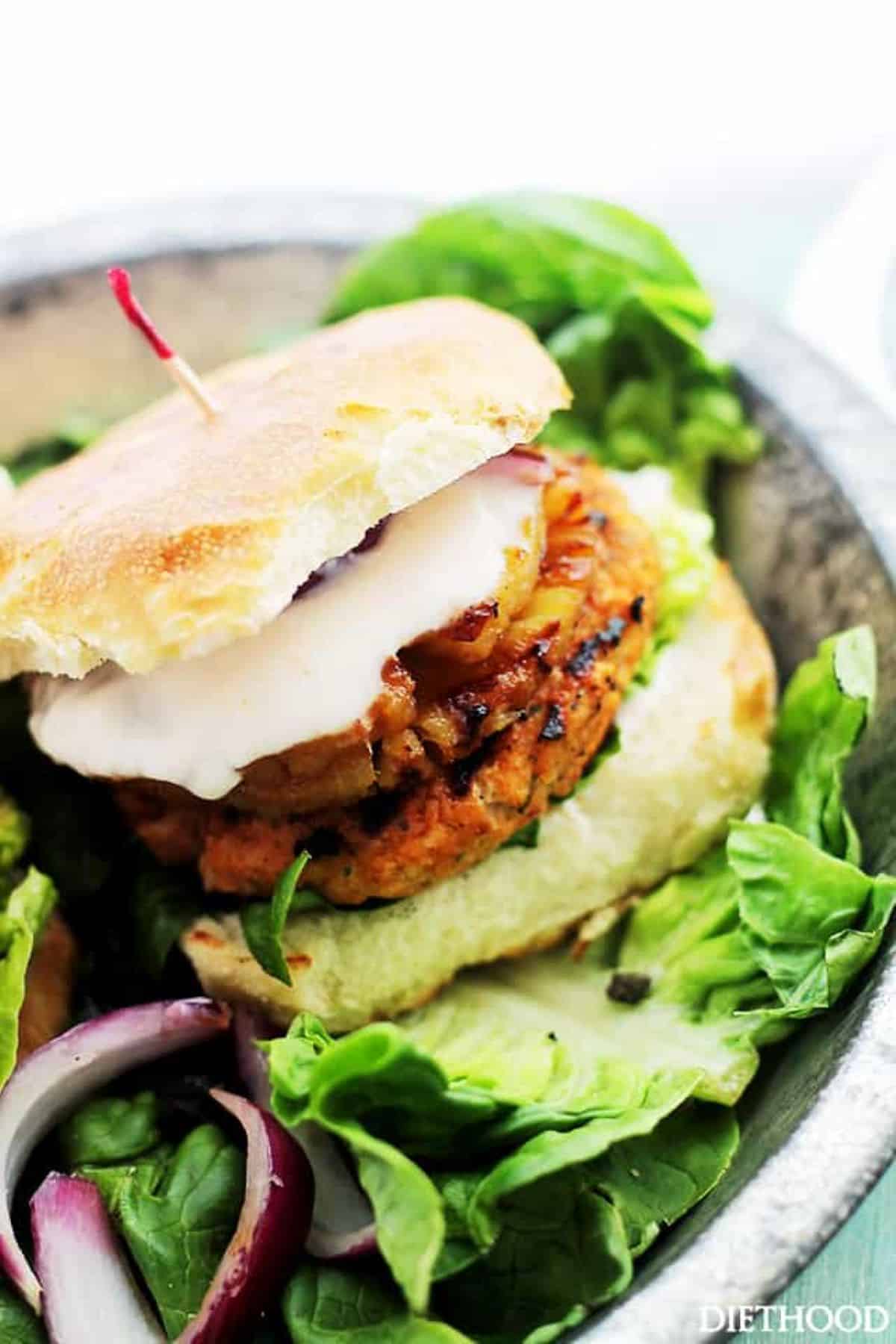 Grilled salmon burger with pineapple, sauce, and toasted bun.