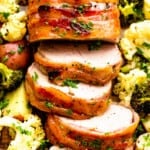 roasted pork tenderloin wrapped in bacon and vegetables spread around it