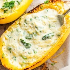 two spaghetti squash boats filled with stringy squash in a heavy cream sauce
