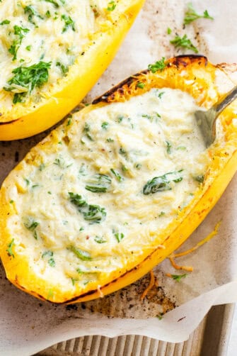 two spaghetti squash boats filled with stringy squash in a heavy cream sauce