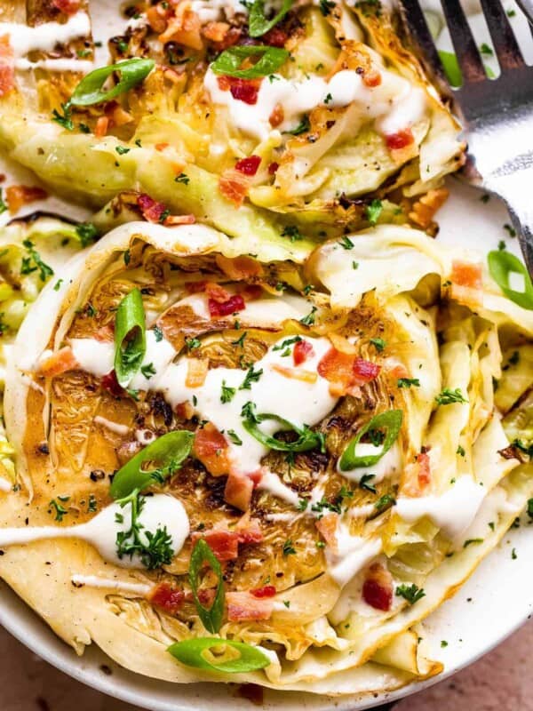 two grilled cabbage steaks topped with ranch and bacon