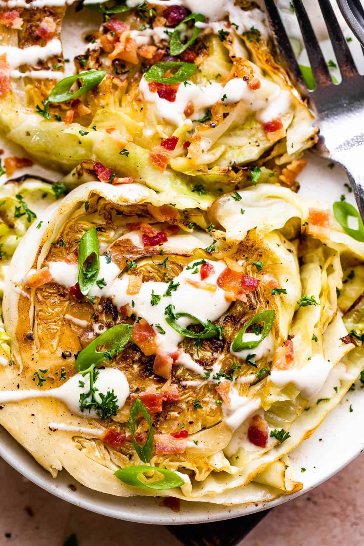 two grilled cabbage steaks topped with ranch and bacon