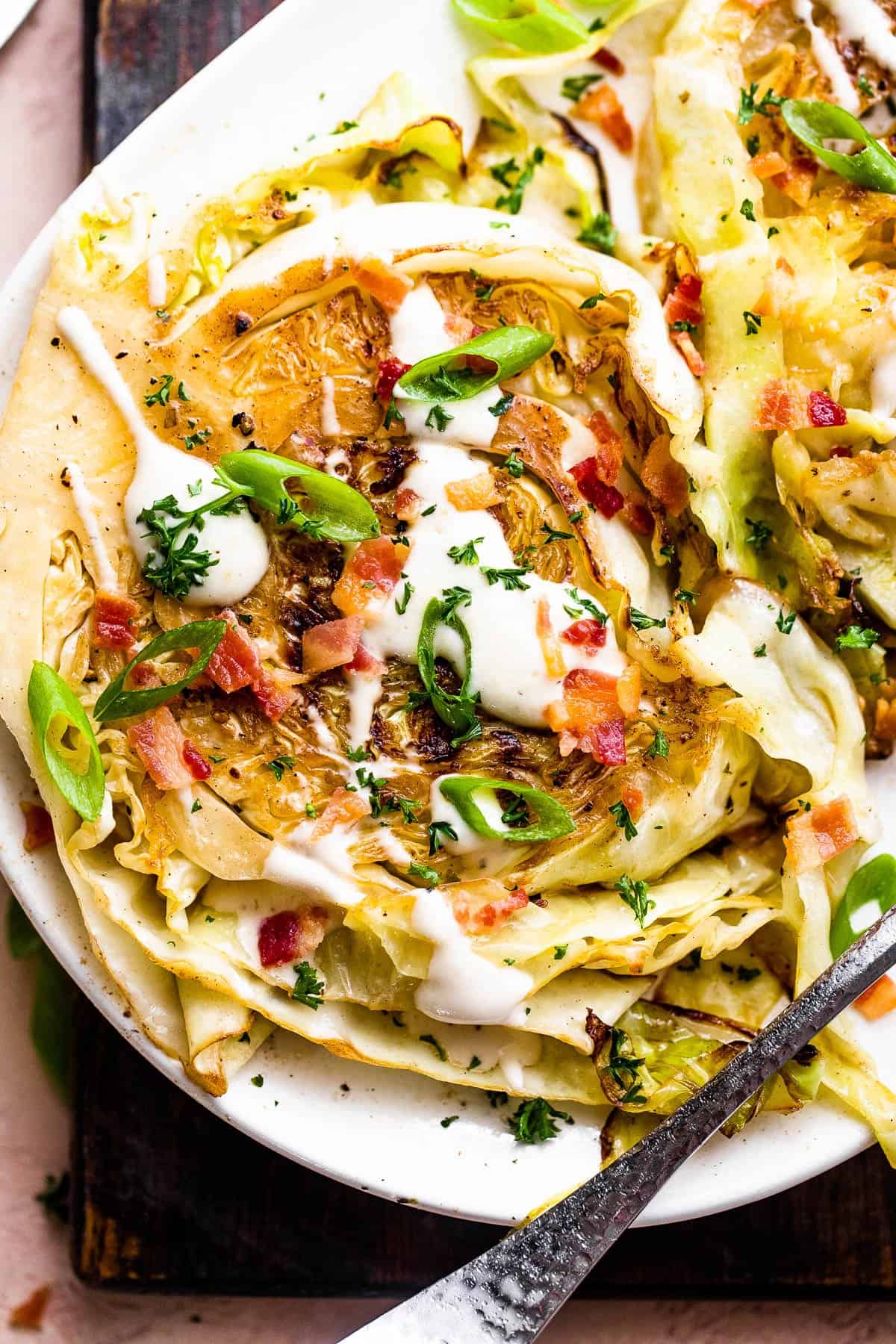 two grilled cabbage steaks topped with ranch and bacon