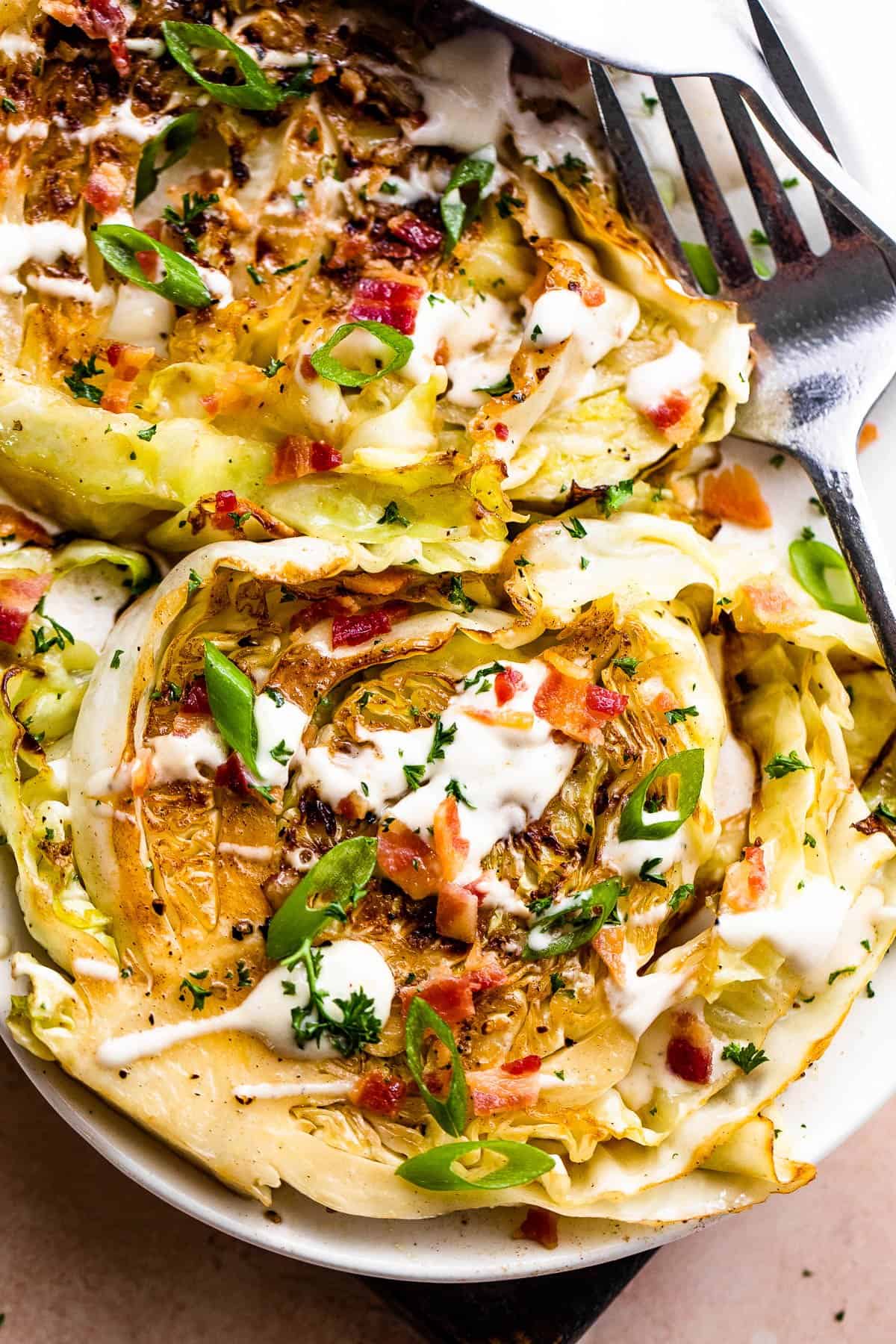 two grilled cabbage steaks topped with ranch and bacon