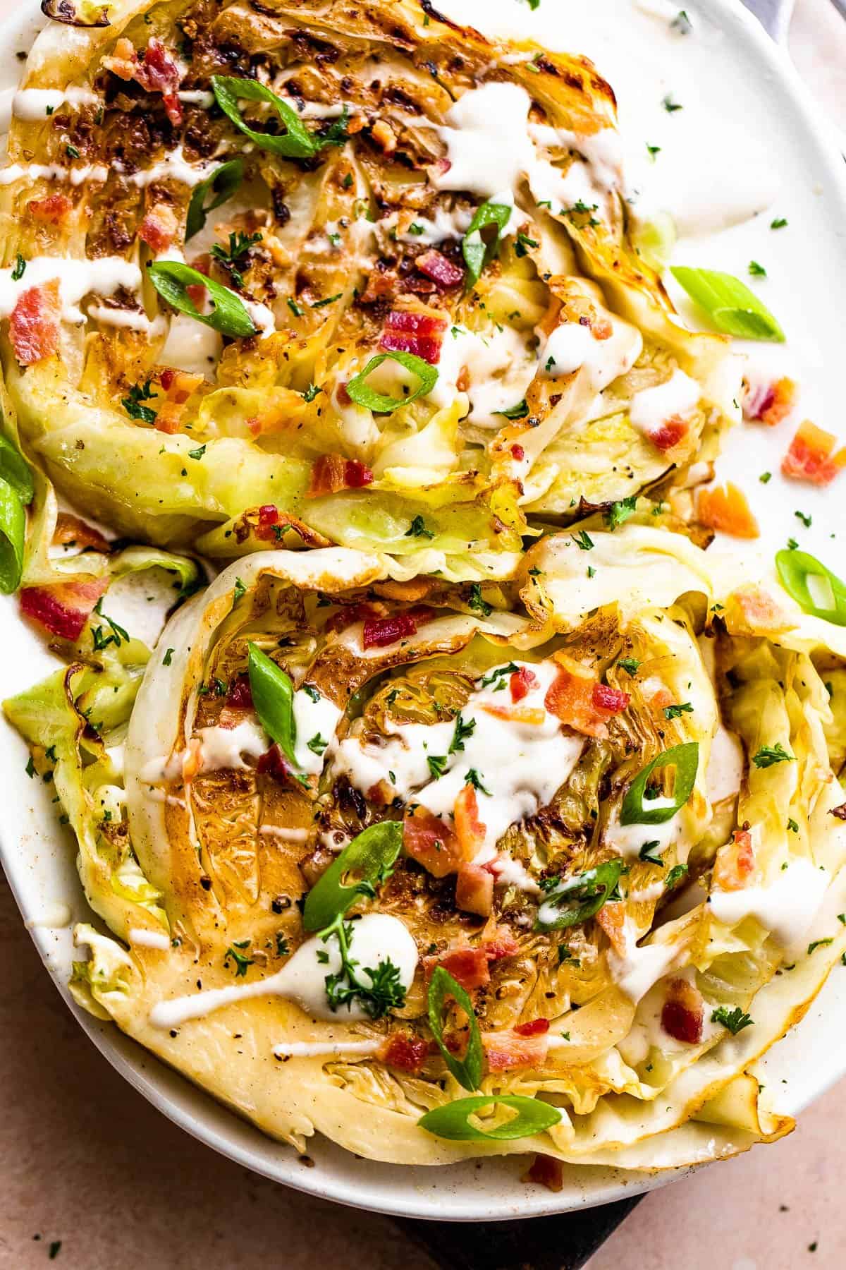 two grilled cabbage steaks topped with ranch and bacon