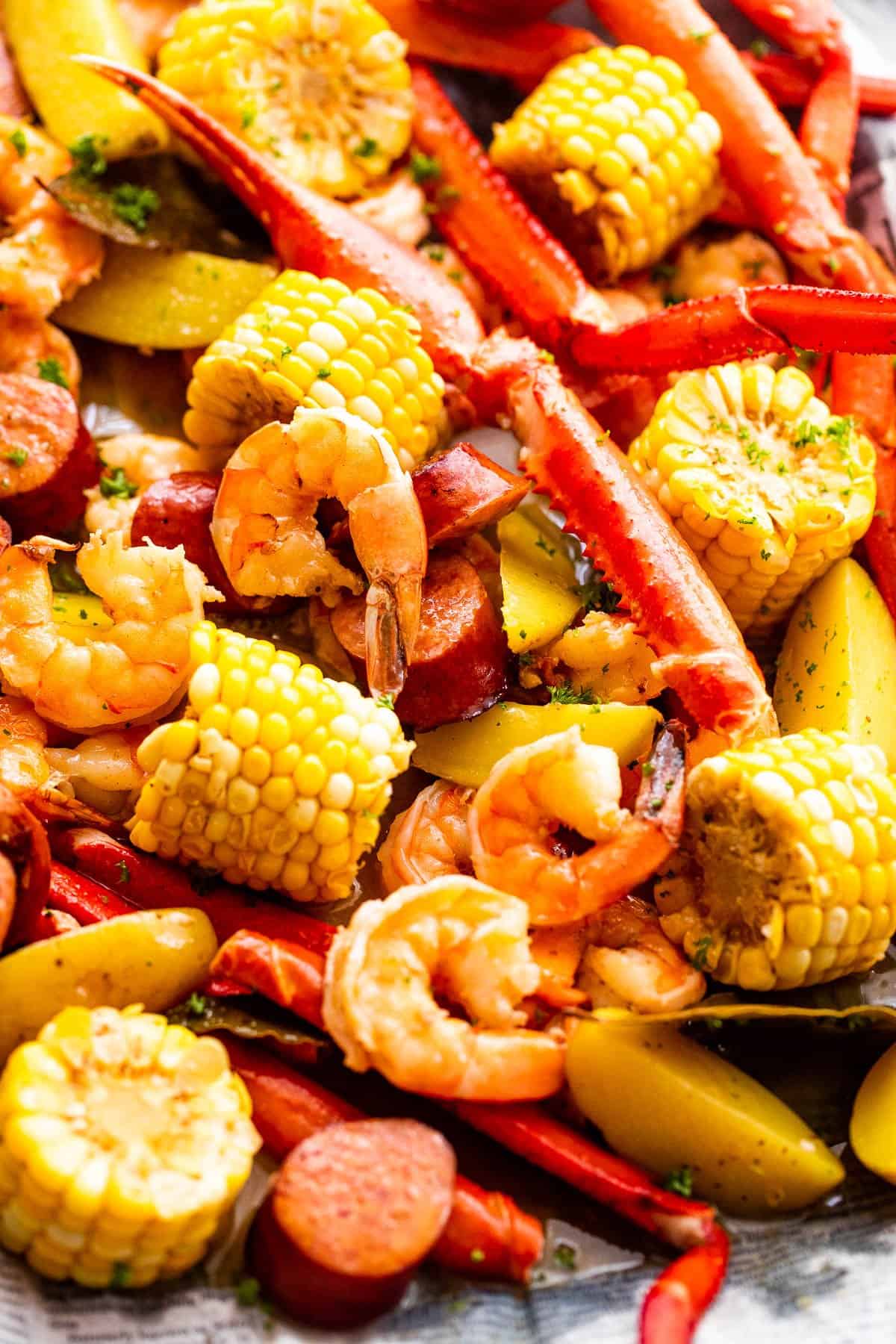 Image of seafood boil with crab legs, shrimp, corn, potatoes, and sausages.