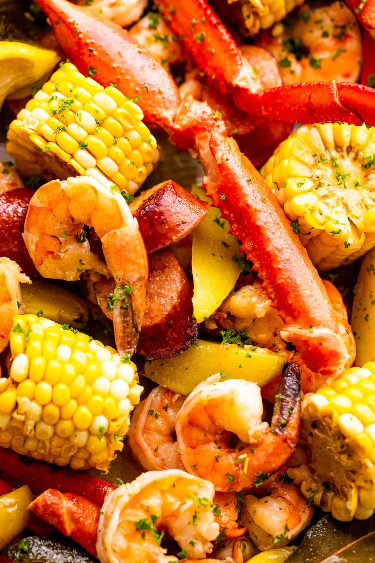 Close-up image of seafood boil with crab legs, shrimp, corn, potatoes, and sausages.