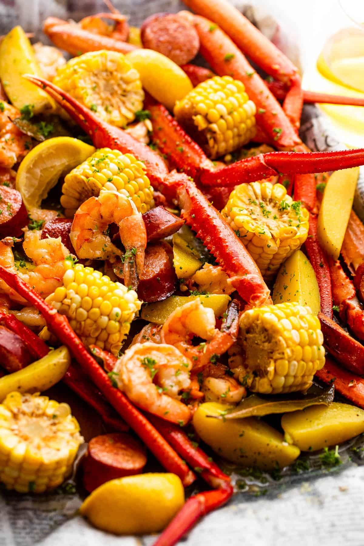 Crab legs, shrimp, and corn served on a baking sheet.