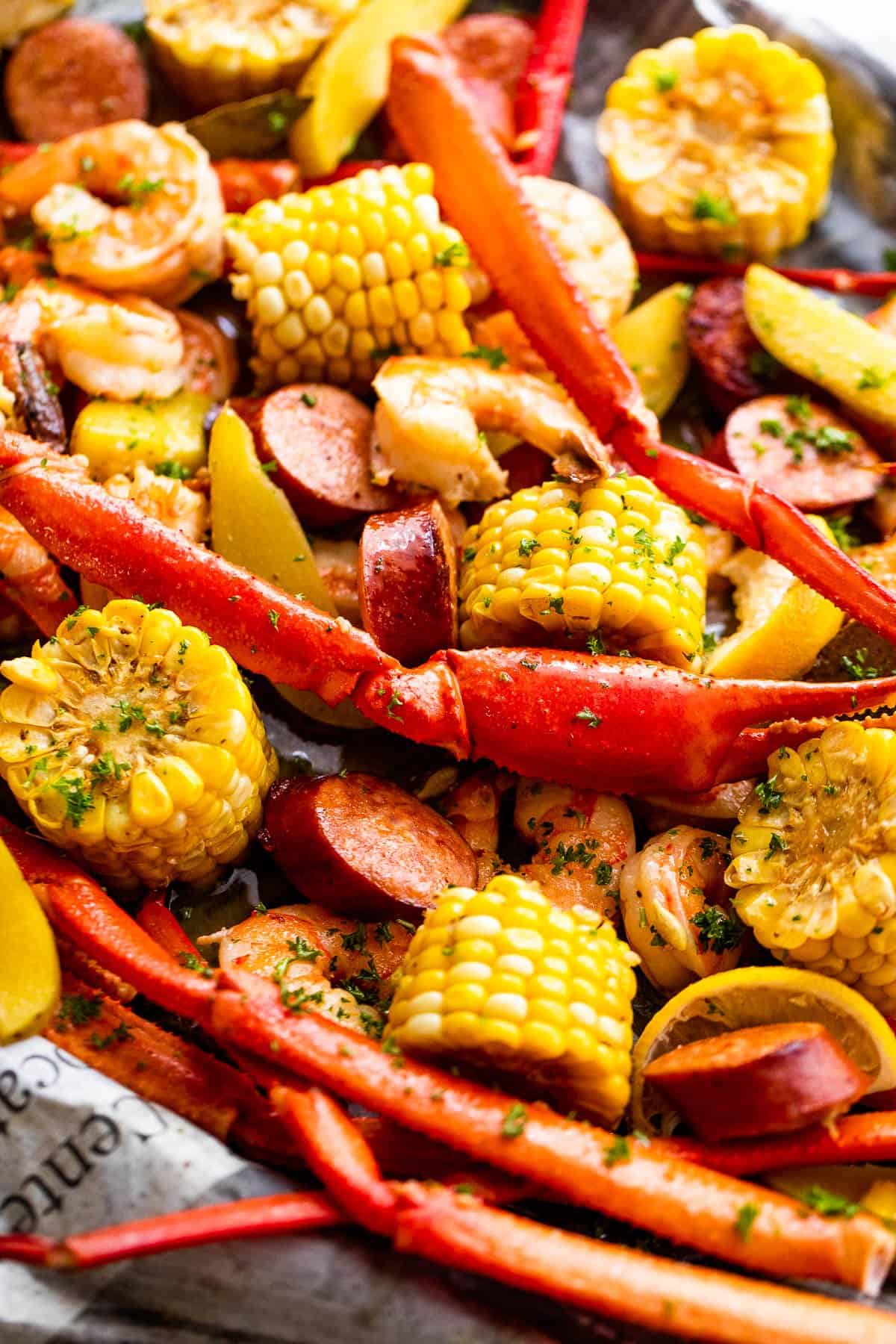 corn, shrimp, crab legs, sausages, and potatoes arranged on newspapers