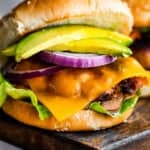 turkey burger with cheese, avocado, and a slice of red onion, set in between sesame seed buns