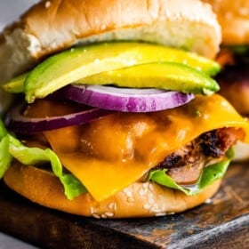 turkey burger with cheese, avocado, and a slice of red onion, set in between sesame seed buns