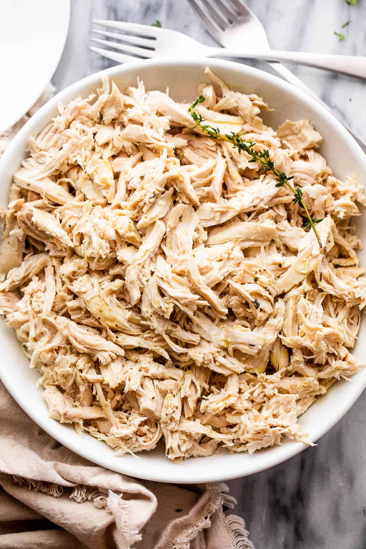 shredded boiled chicken breasts in a white serving bowl