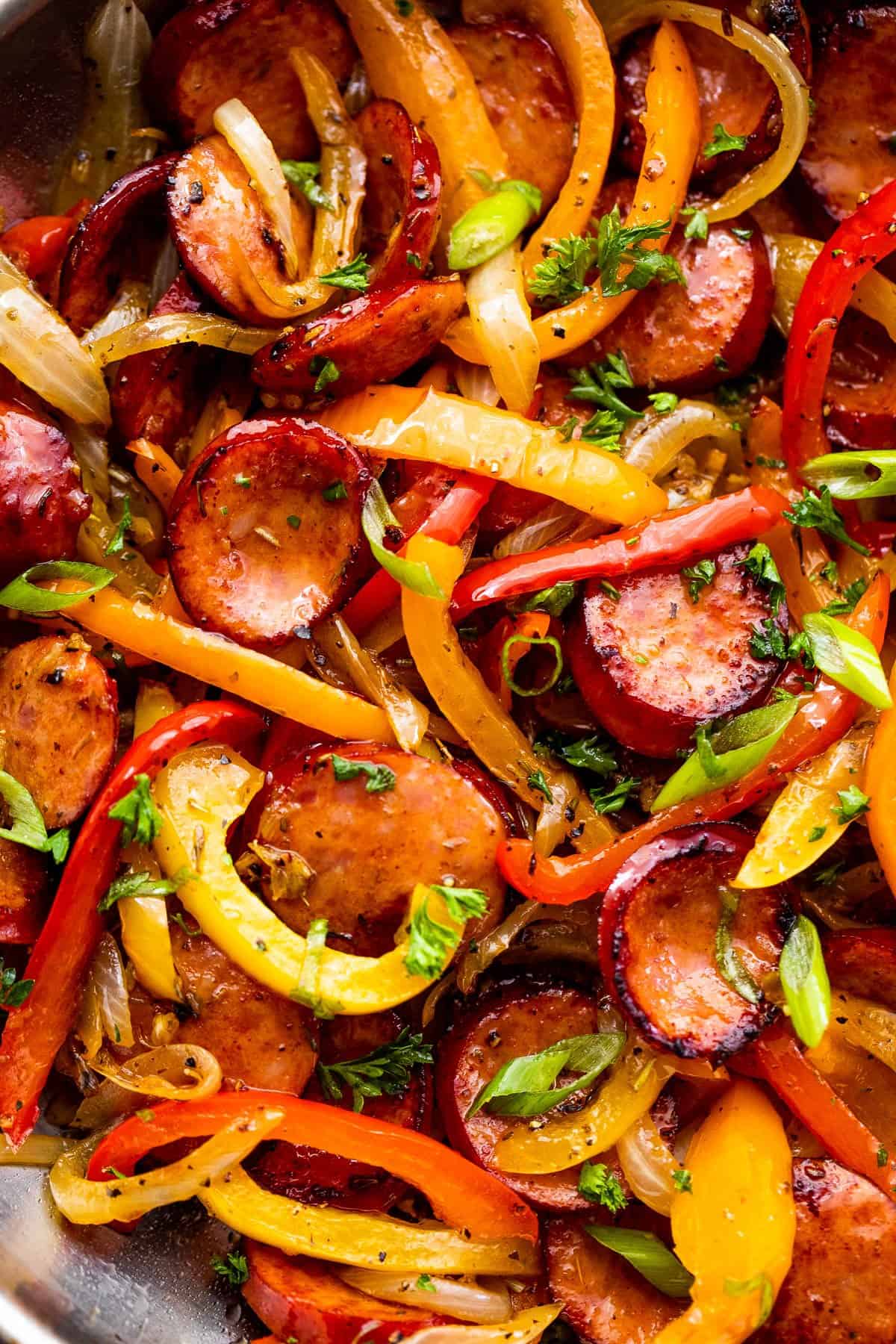 Up close photo of sliced bell peppers, andouille sausage slices, and onions.