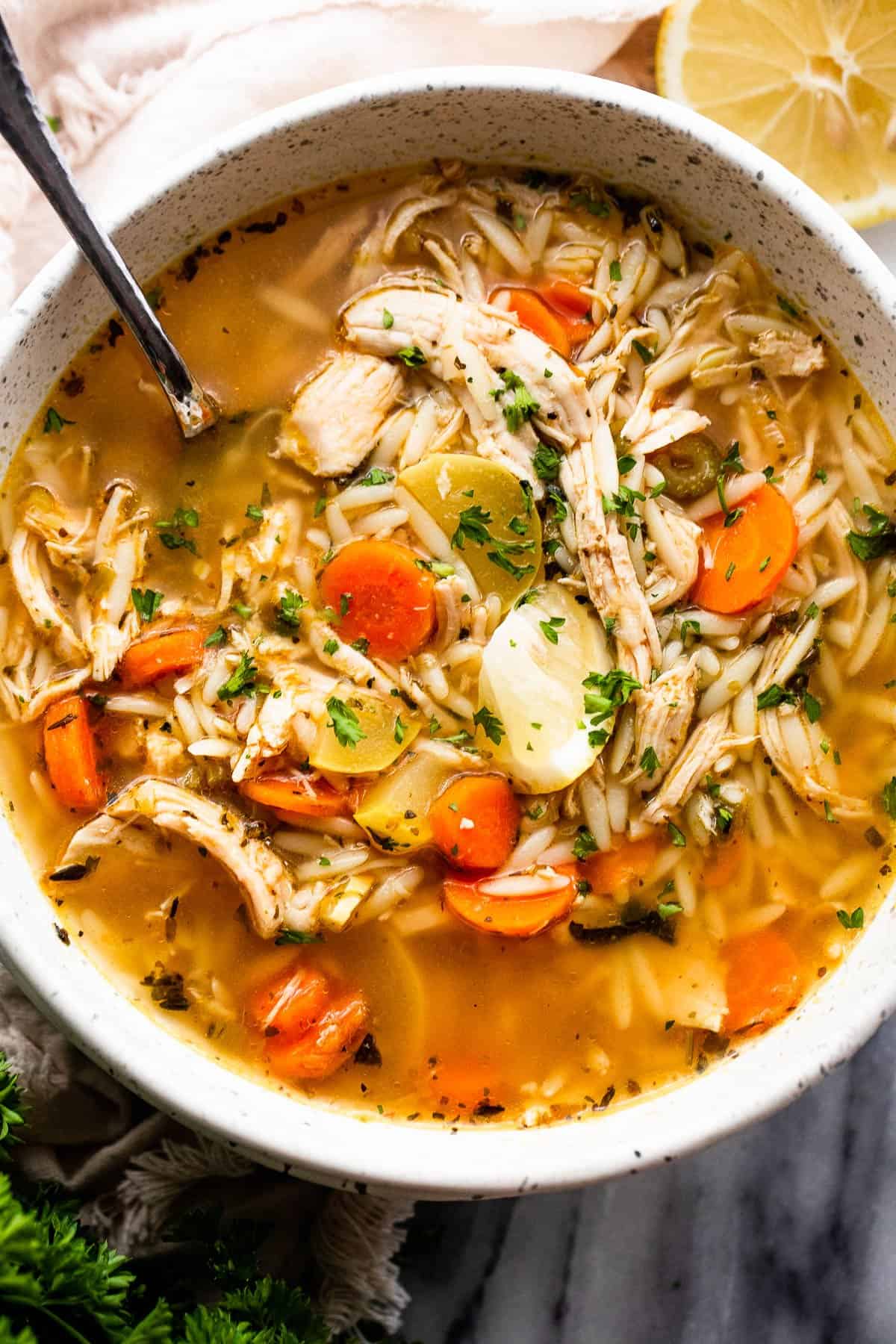 chicken orzo soup served in a white soup bowl with a spoon