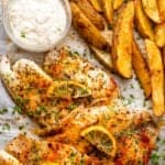 Tilapia fish fillets served with potato wedges and tartar sauce.