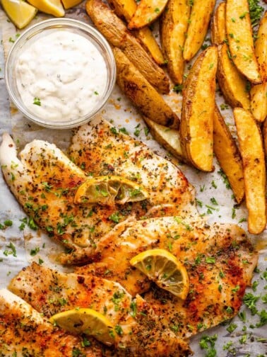Tilapia fish fillets served with potato wedges and tartar sauce.