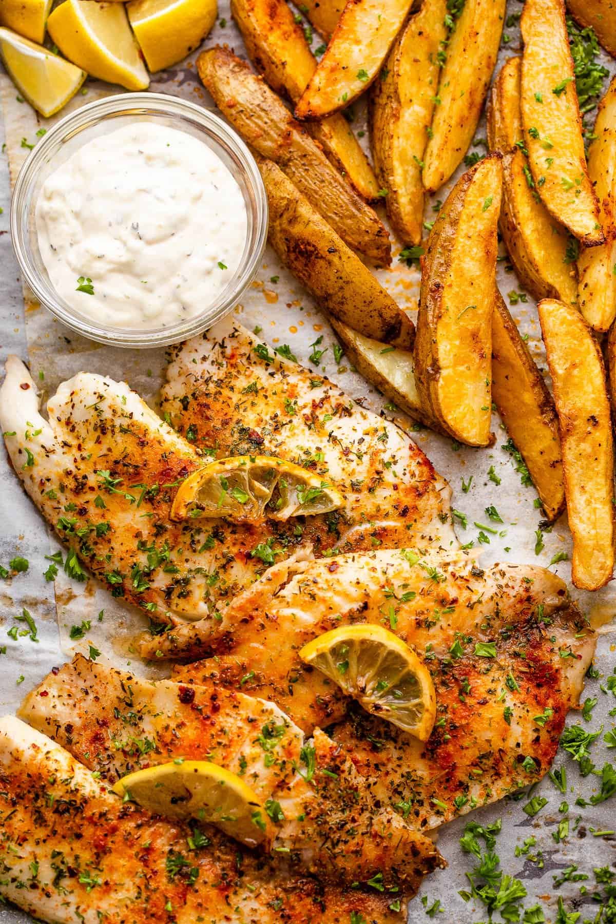 Tilapia fish fillets served with potato wedges and tartar sauce.