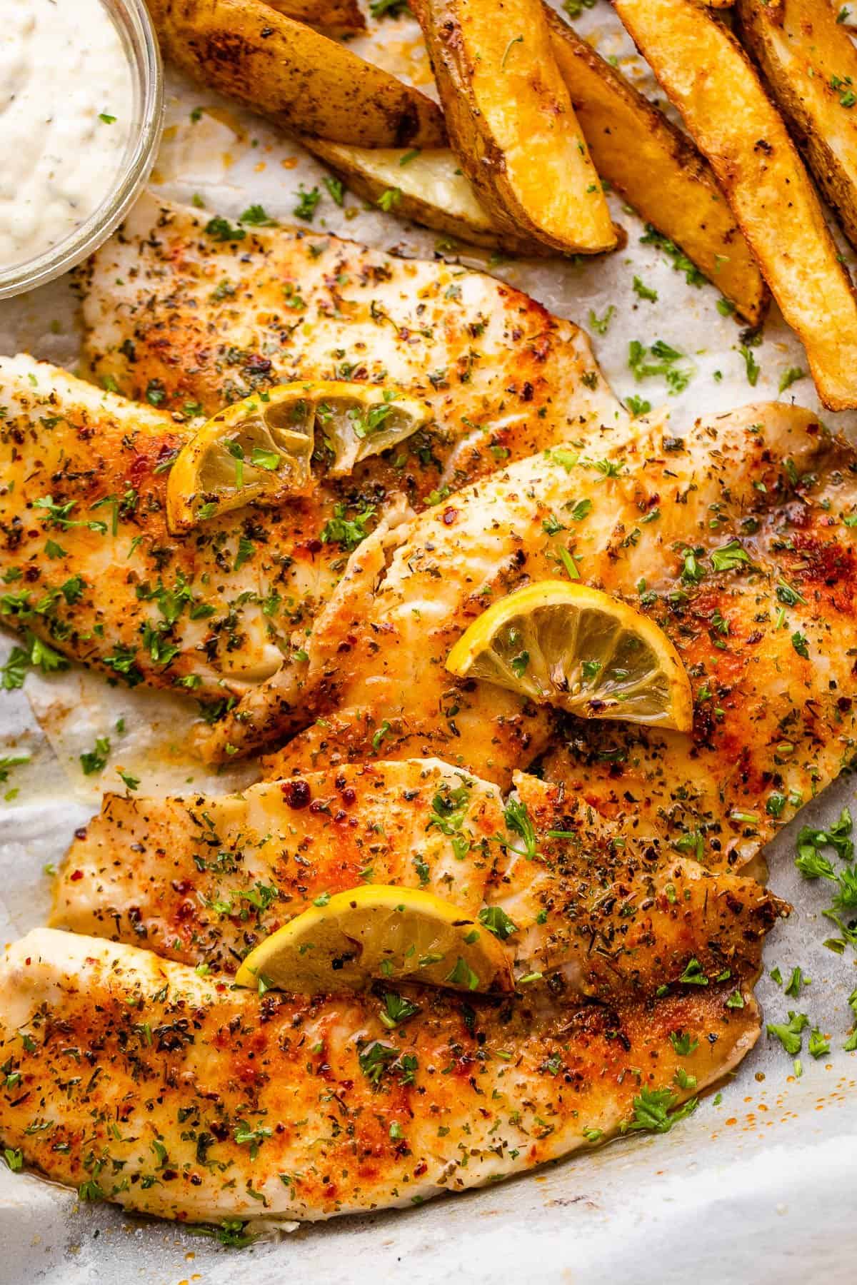 three tilapia fish fillets topped with lemon slices.