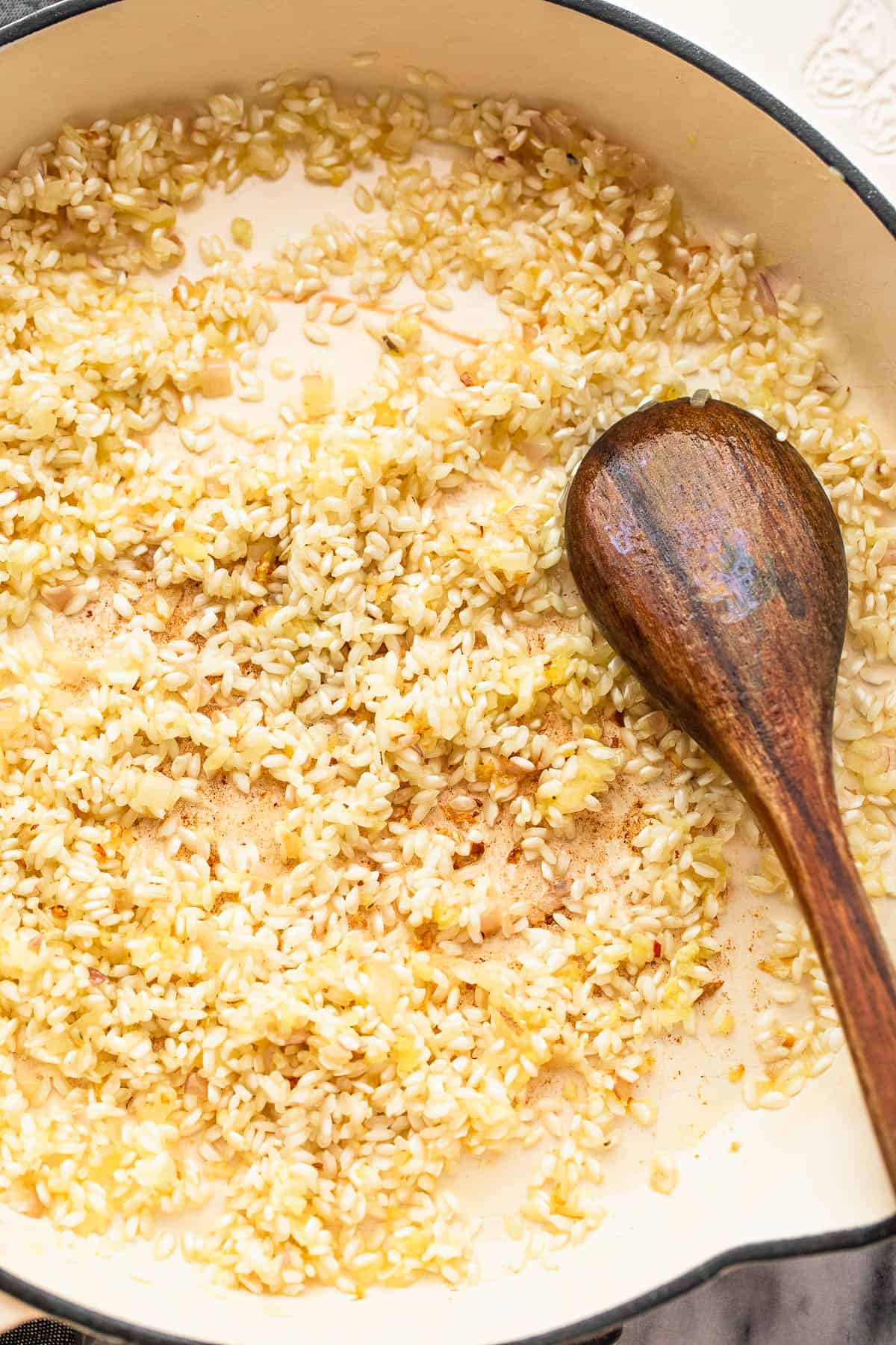 frying arborio rice in a white skillet