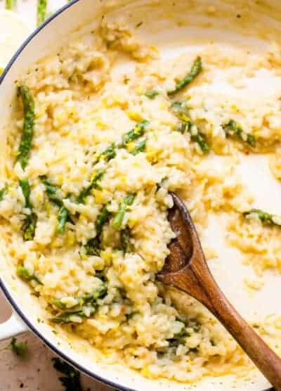wooden spoon stirring through cooked risotto with asparagus
