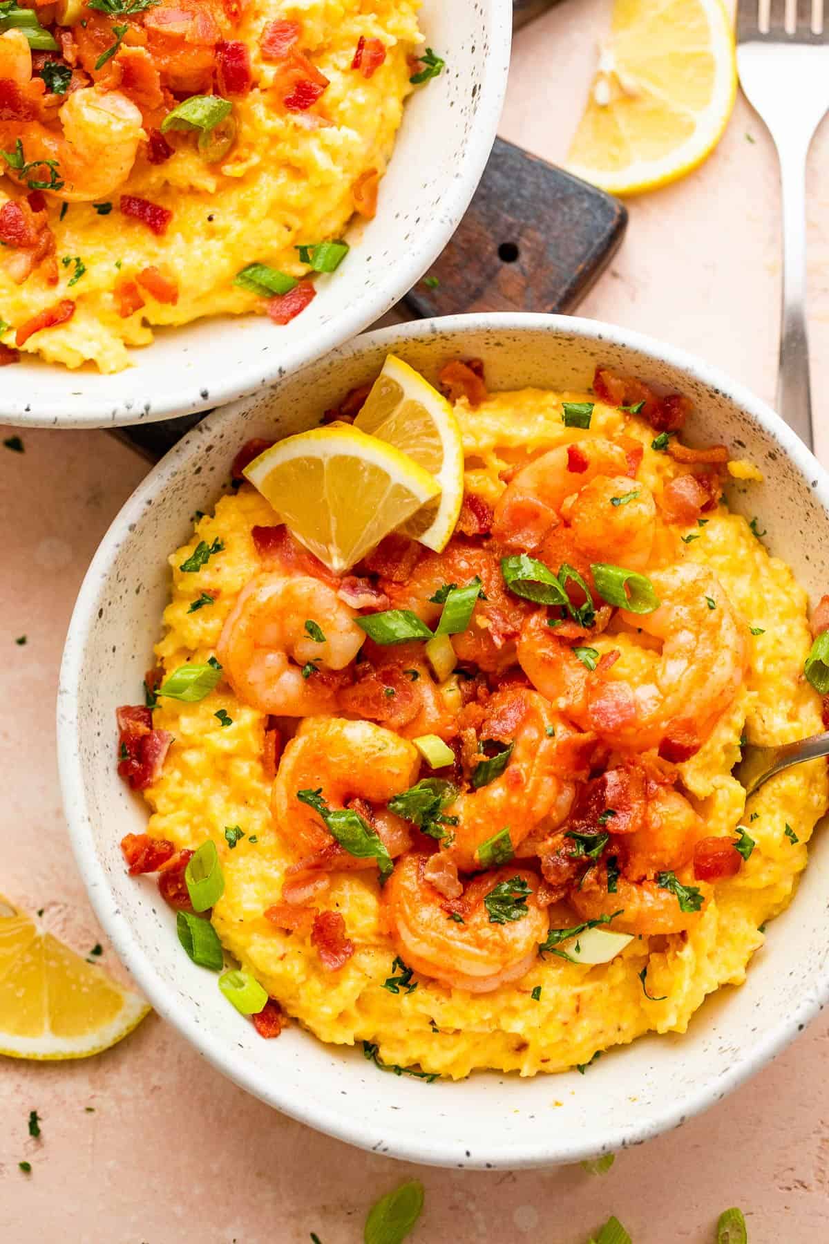 overhead shot of two bowls with slow cooker grits topped with shrimp, bacon, and green onions