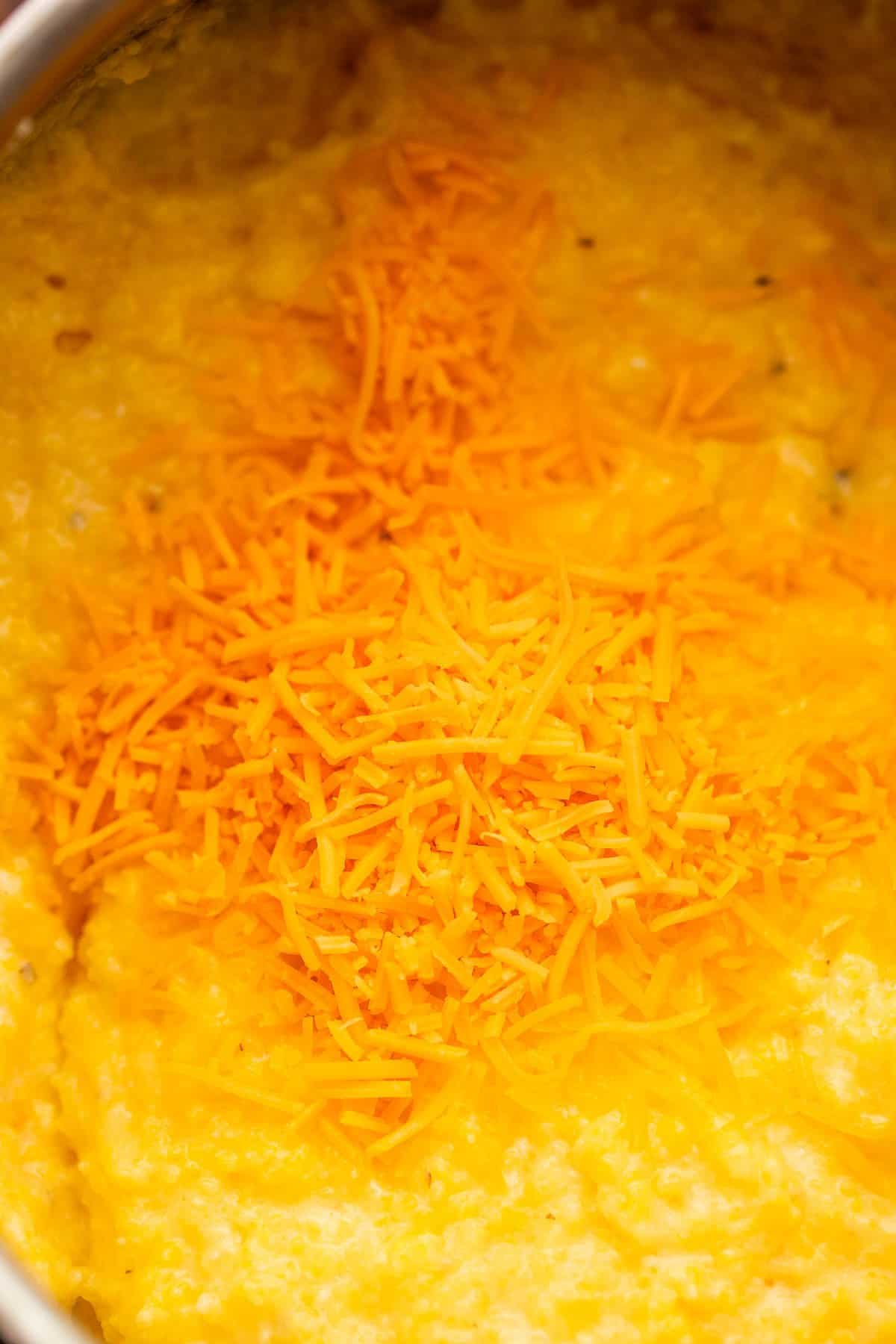 adding shredded cheese to slow cooked grits