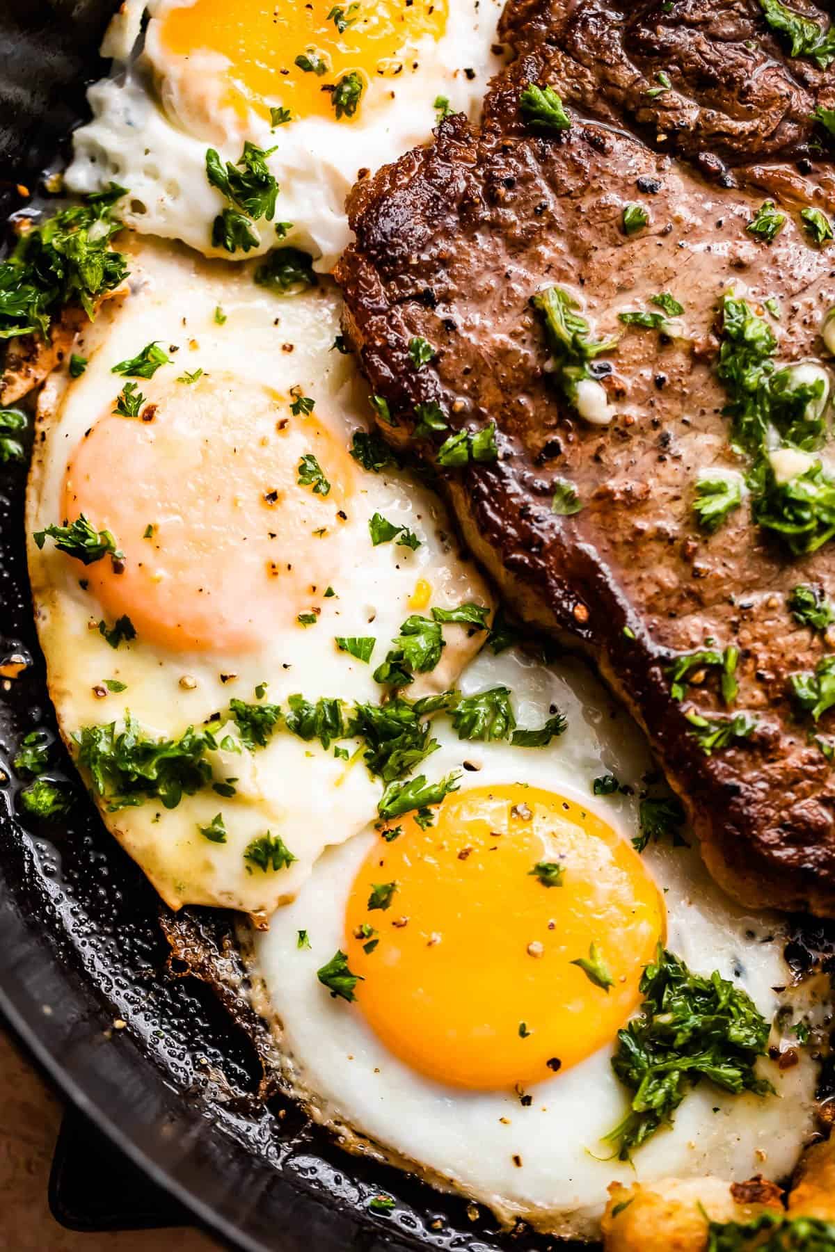 up close shot of three eggs cooked over easy and arranged near t-bone steak