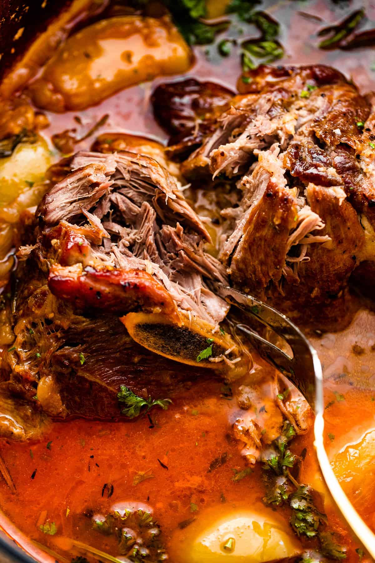 Serving fork tearing into a braised pork shoulder.