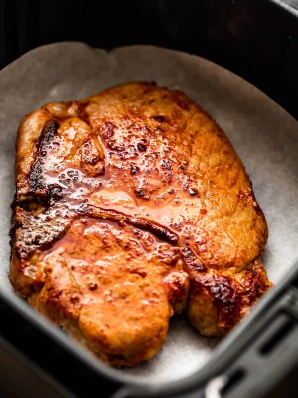 cooked bone in pork chop in an air fryer basket