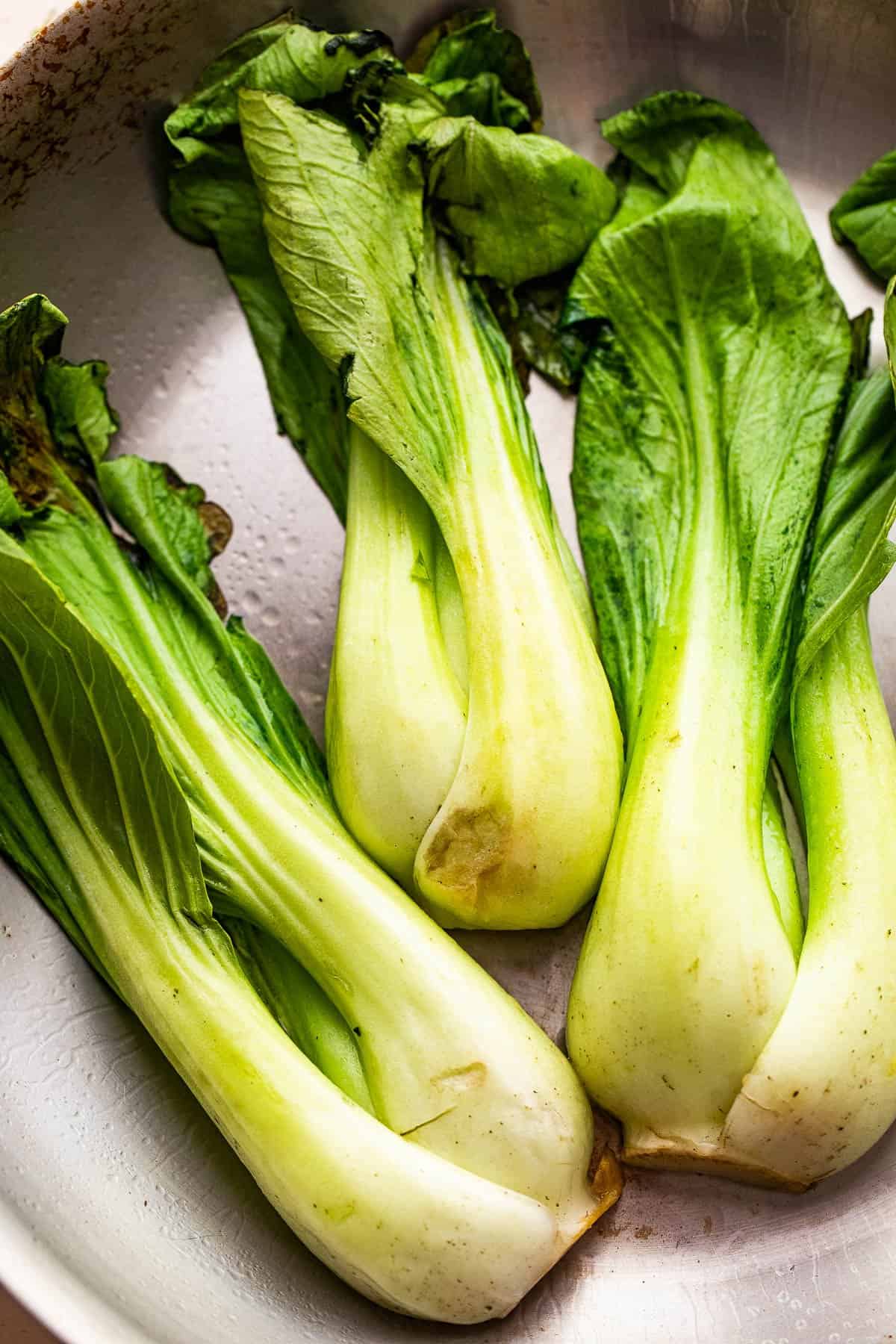 raw bok choy in a stainless steel skillet