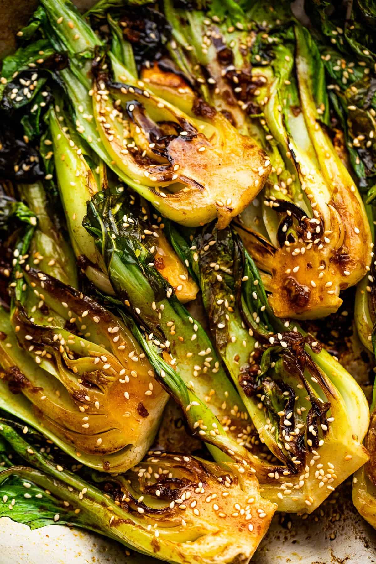 close up of pan fried halved baby bok choy topped with soy dressing and sesame seeds