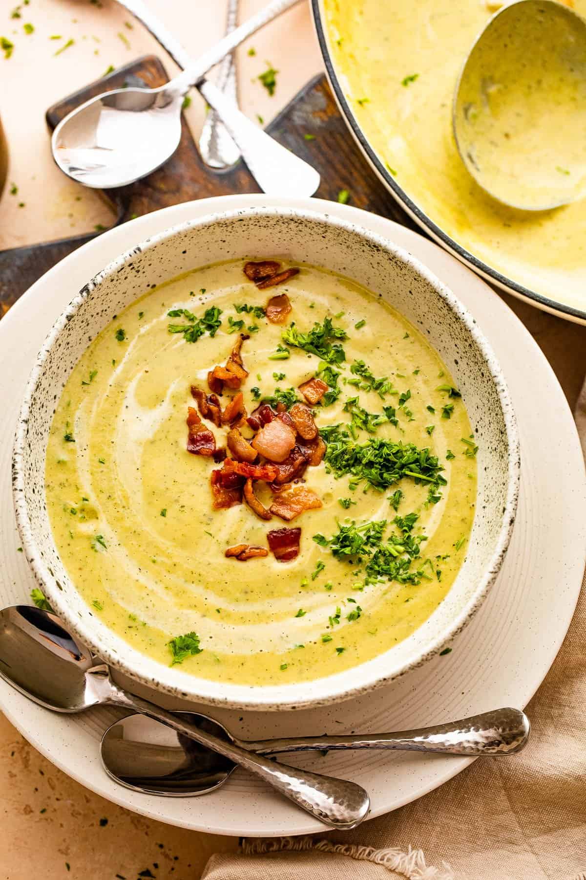overhead shot of soup bowl with cream of zucchini soup garnished with bacon and parsley