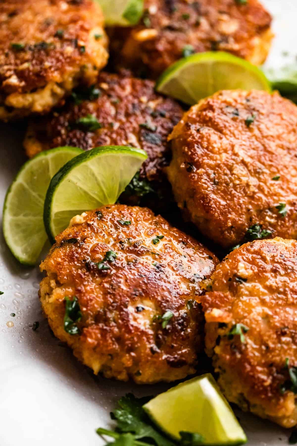 Close up shot of air fryer fish cakes set on a platter with a garnish of lime slices.