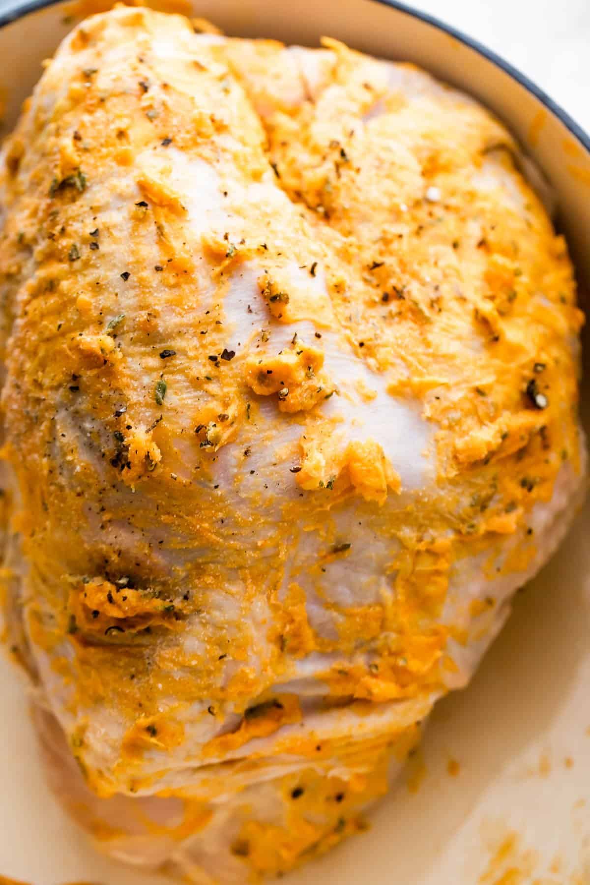raw turkey breast covered with herbs and butter.