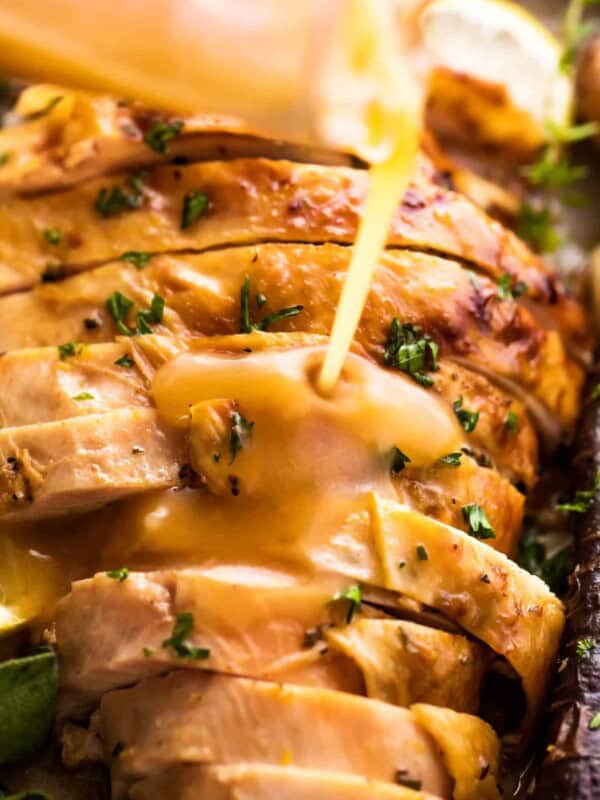 pouring gravy over slices of turkey breast.