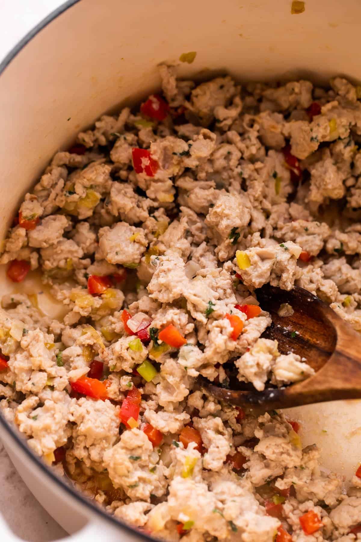 Cooking ground turkey meat in a white dutch oven.