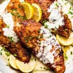 Three turkey cutlets in a skillet topped with cream sauce.