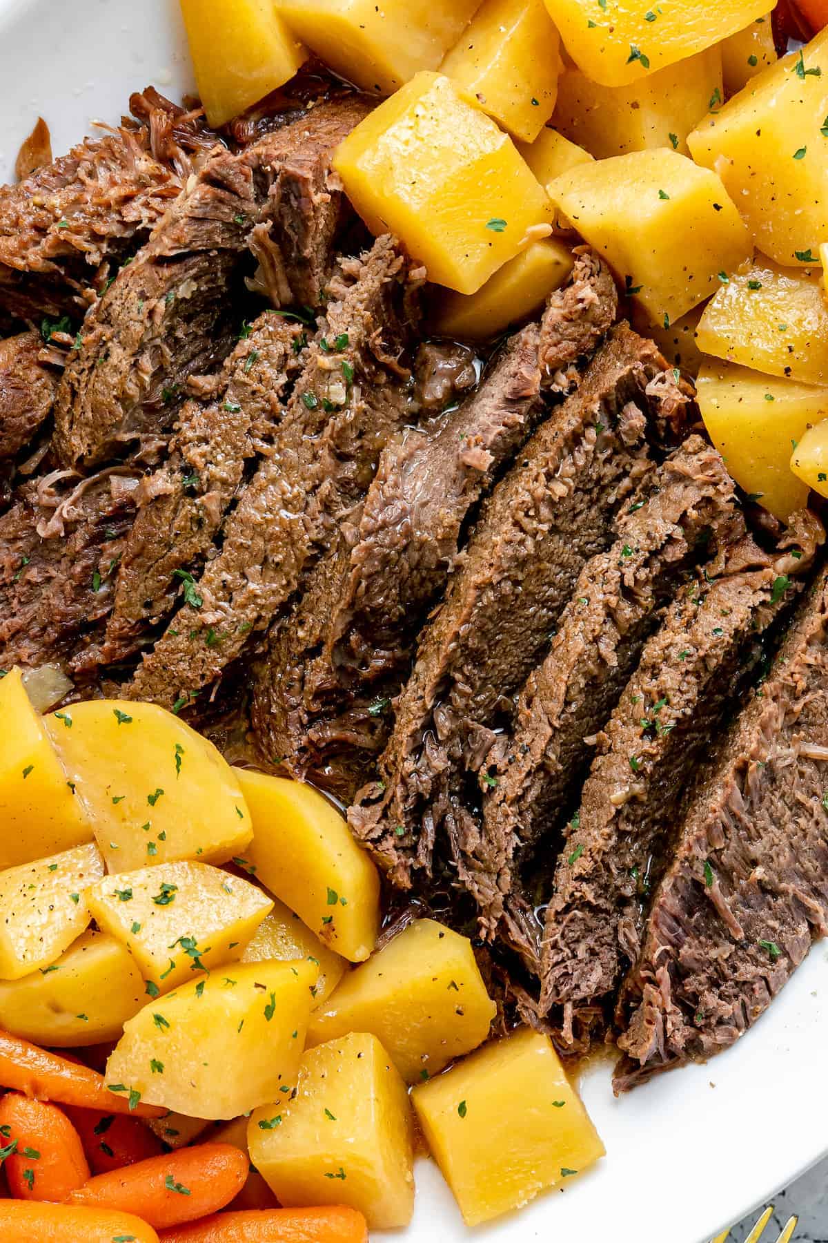 POT ROAST served on a plate with carrots and potatoes