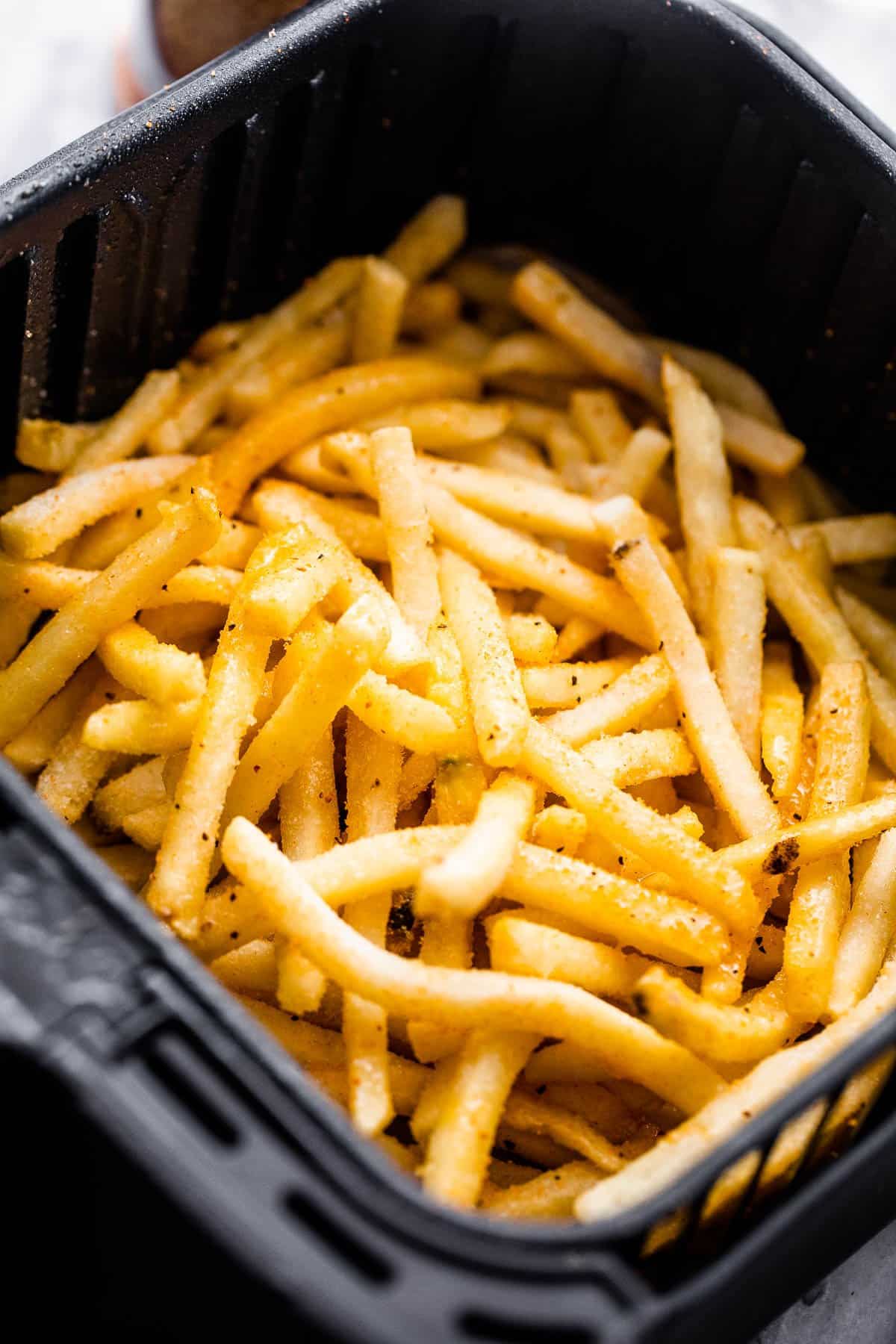 frozen french fries in a black air fryer basket.