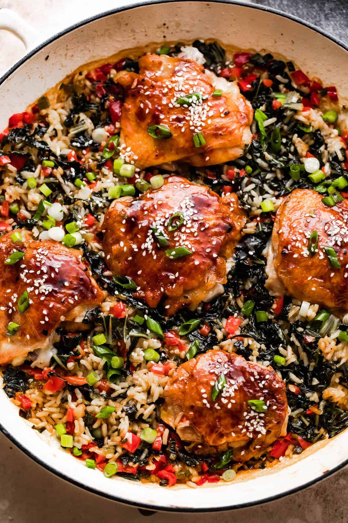 five chicken thighs cooking in a baking dish with rice and bok choy.