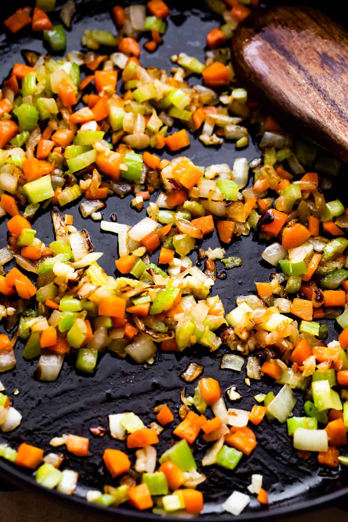 cooking diced onions and carrots in a dark skillet.