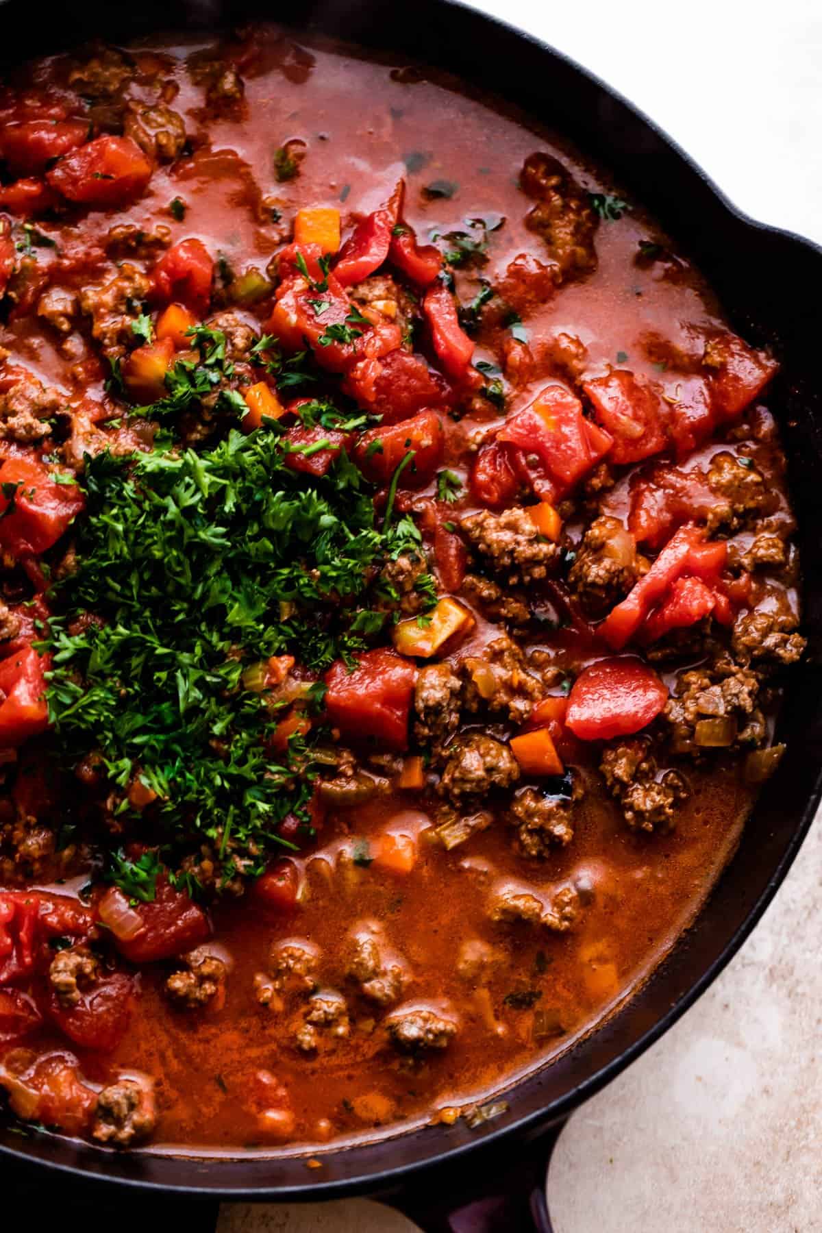 cooking down tomatoes and ground beef for homemade bolognese sauce.