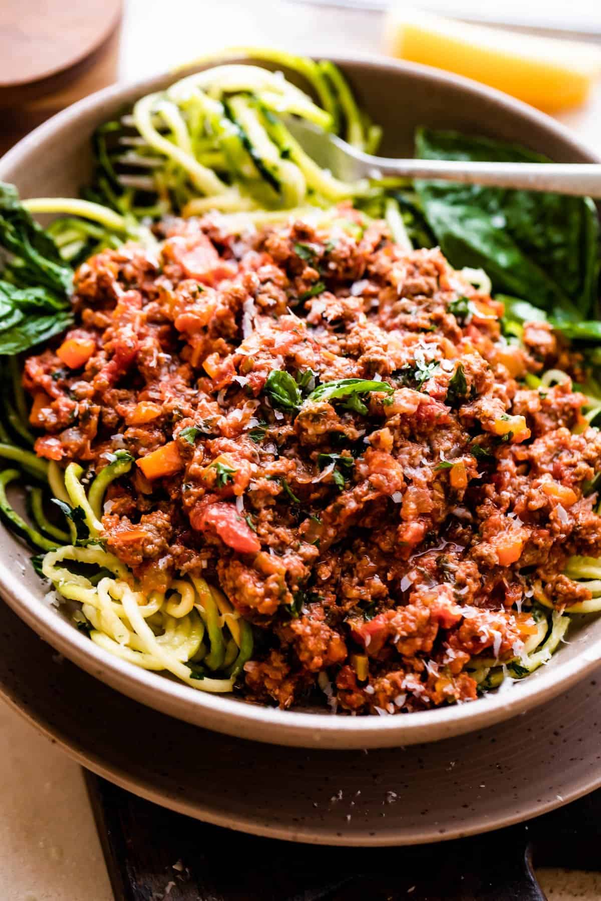 side shot of a bowl filled with zoodles and topped with Homemade Bolognese Sauce