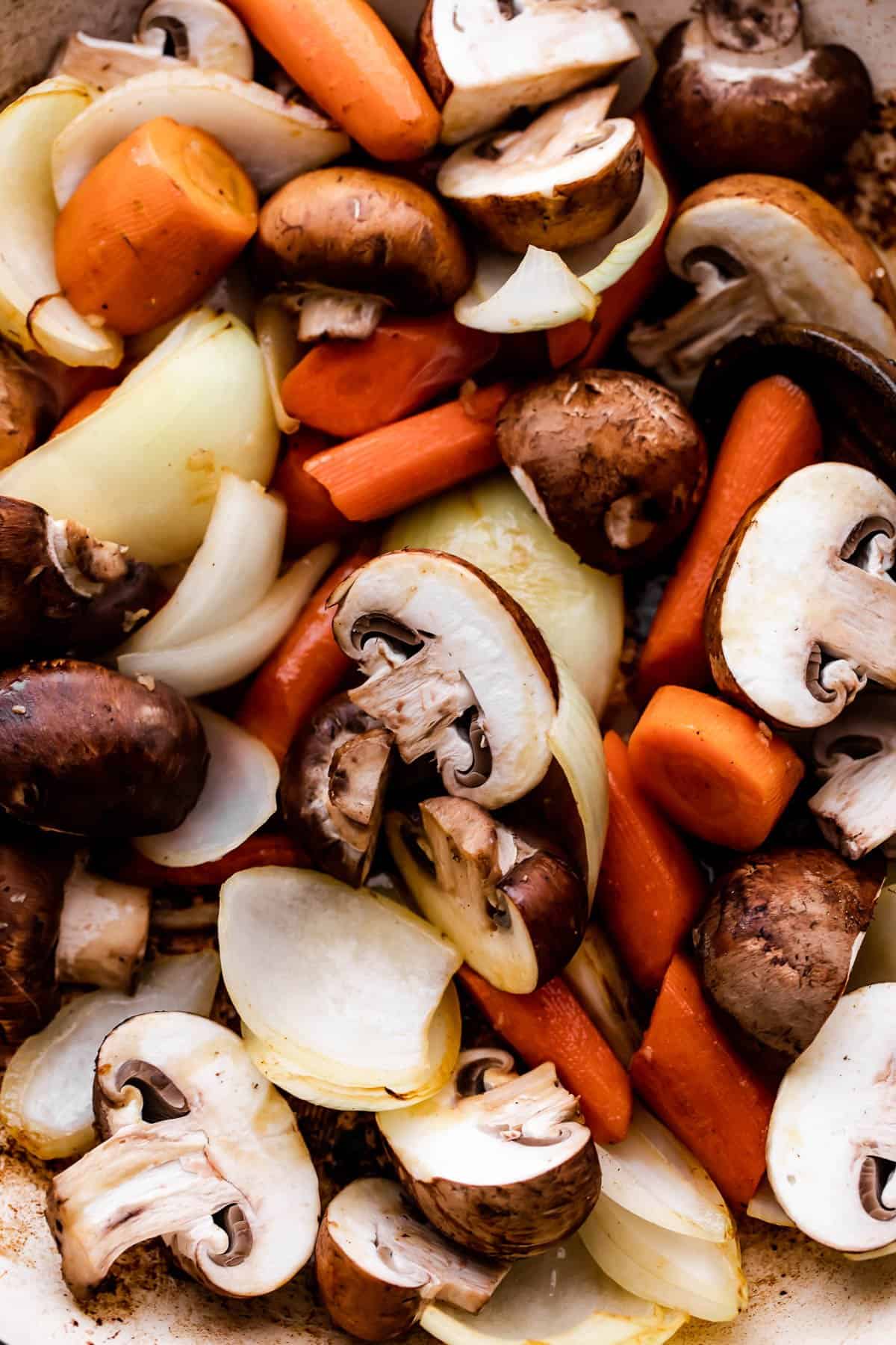 Close-up shot of sliced mushrooms, carrots, and onions.