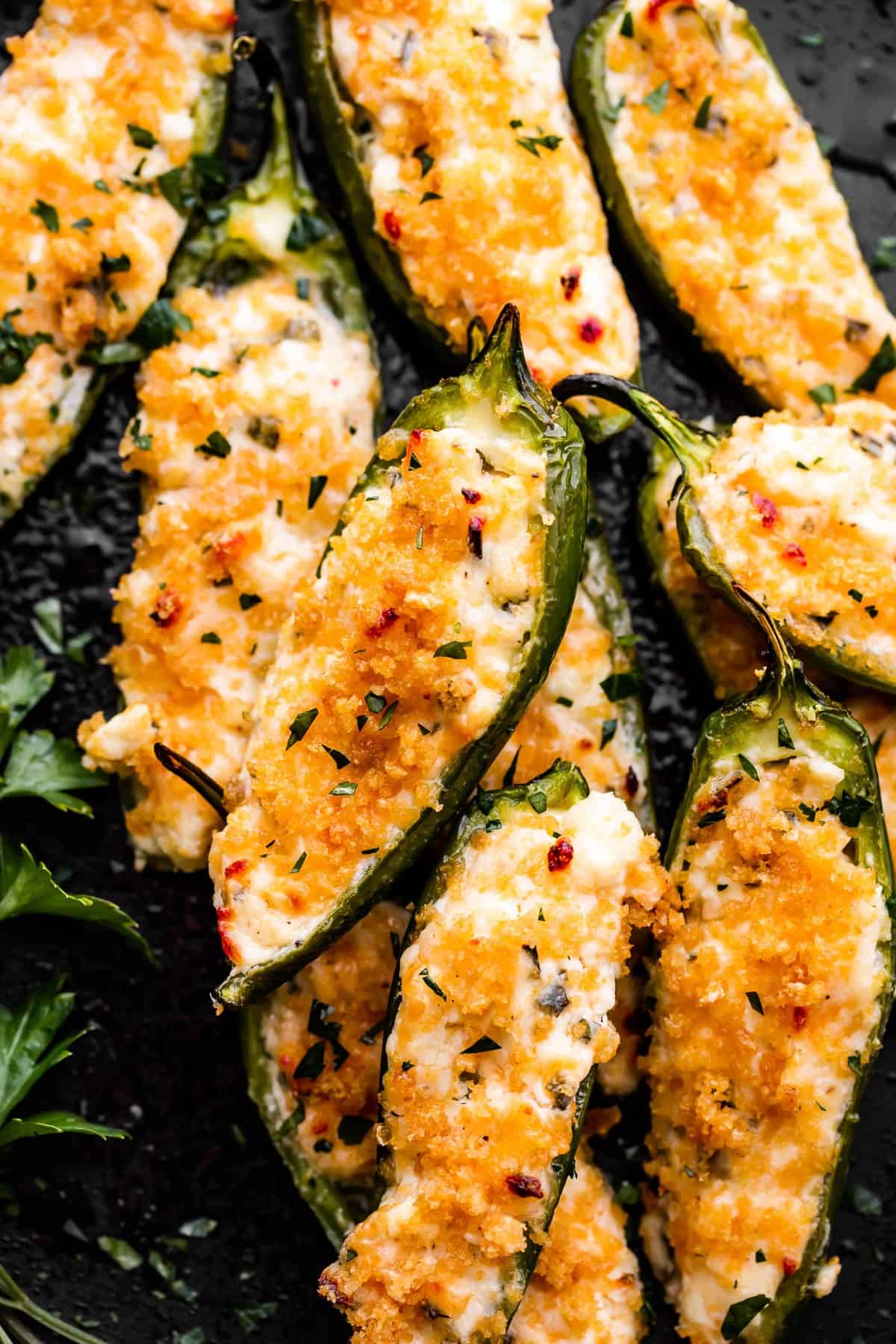 Air Fryer Jalapeno Poppers arranged on a round black plate and garnished with parsley.