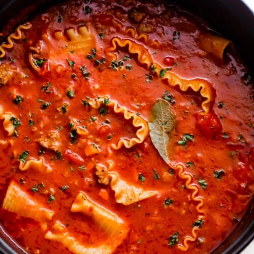 overhead shot of a dark dutch oven filled with lasagna noodles in tomato broth