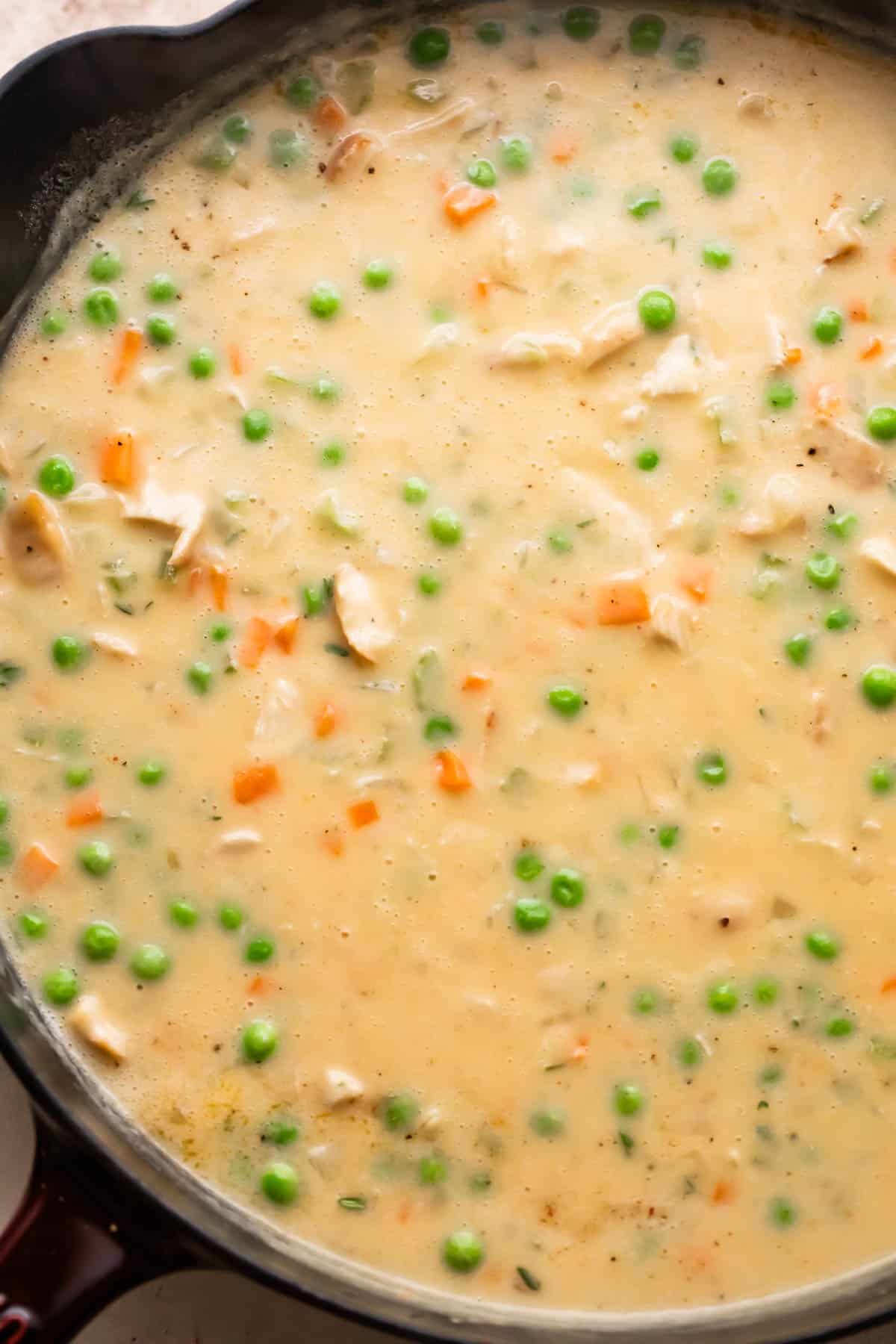 creamy mixture of turkey pot pie with peas and carrots.