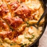 photo of turkey pot pie in a skillet topped with puff pastry crust, and a spoon inside the mixture.