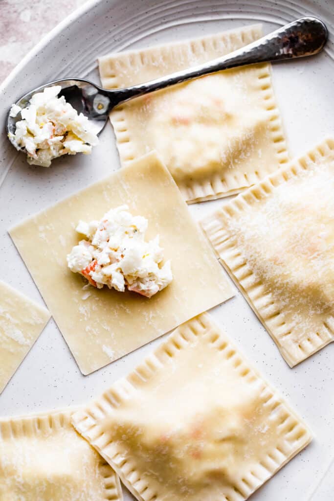 A mixture of lobster and cream cheese spooned onto a wonton wrapper.