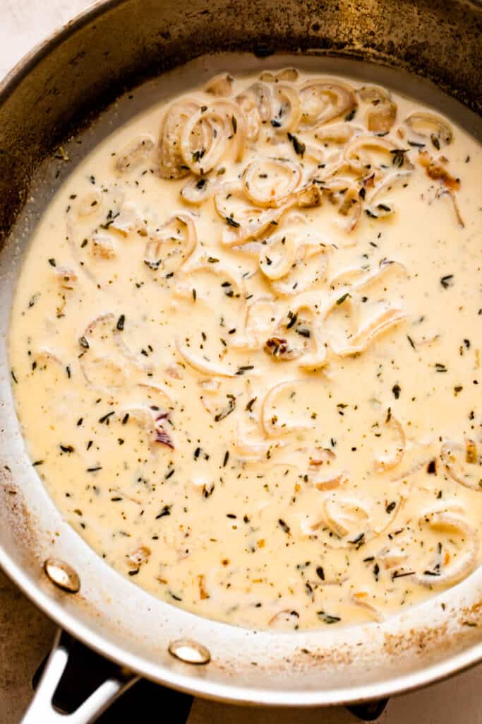 Cooking creamy sauce with shallots in a skillet.